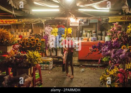 Una bella donna cambogiana con un bouquet di rose in una bancarella di strada che vende fiori di notte. Il mercato centrale, Phnom Penh, Cambogia. © Kraig Lieb Foto Stock