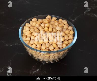 I chicchi di garbanzo crudi preimbevuti in un recipiente di vetro sul piano della cucina pronti per la cottura Foto Stock