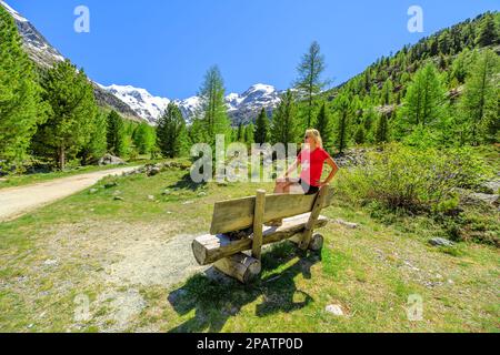 Donna con t-shirt con bandiera svizzera sul sentiero di trekking per il ghiacciaio di Morteratsch in Svizzera. Il più grande ghiacciaio della catena Bernina delle Alpi Bundner in Foto Stock