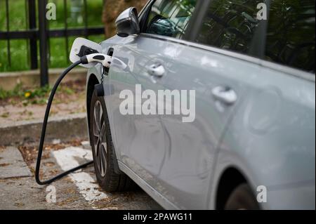 Auto elettrica con cavo di alimentazione collegato durante la ricarica Foto Stock