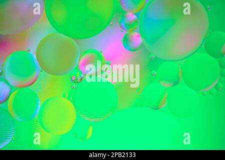 Sfondo astratto multicolore con cerchi in olio sulla superficie dell'acqua con sfondo verde Foto Stock