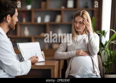 Medico ginecologo che mostra Clipboard con risultati di test medico per la donna in gravidanza stressata Foto Stock