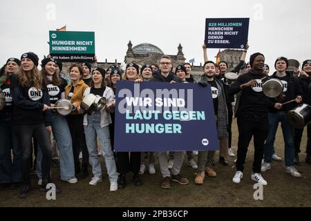 12 marzo 2023, Berlino, Germania: Il 12 marzo 2023, un gruppo di giovani ha protestato davanti all'edificio del Reichstag di Berlino per richiamare l'attenzione sul fatto che 828 milioni di persone in tutto il mondo soffrono ancora di fame. Hanno bevuto sulle pentole e hanno tenuto i segni con lo slogan ''forte contro la fame.'' La ONE Campaign, nota anche come ONE, è un’organizzazione internazionale, non partisan e senza scopo di lucro che sostiene e promuove campagne per combattere la povertà estrema e le malattie prevenibili, in particolare in Africa, sensibilizzando l’opinione pubblica e facendo pressioni sui leader politici affinché sostengano politiche e programmi che fanno risparmiare Foto Stock