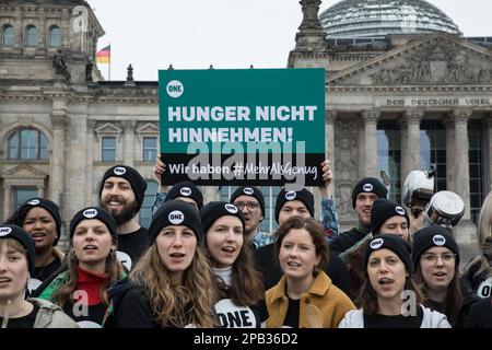 12 marzo 2023, Berlino, Germania: Il 12 marzo 2023, un gruppo di giovani ha protestato davanti all'edificio del Reichstag di Berlino per richiamare l'attenzione sul fatto che 828 milioni di persone in tutto il mondo soffrono ancora di fame. Hanno bevuto sulle pentole e hanno tenuto i segni con lo slogan ''forte contro la fame.'' La ONE Campaign, nota anche come ONE, è un’organizzazione internazionale, non partisan e senza scopo di lucro che sostiene e promuove campagne per combattere la povertà estrema e le malattie prevenibili, in particolare in Africa, sensibilizzando l’opinione pubblica e facendo pressioni sui leader politici affinché sostengano politiche e programmi che fanno risparmiare Foto Stock