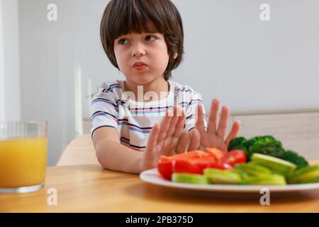 Carino ragazzino che si rifiuta di mangiare verdure a casa Foto Stock