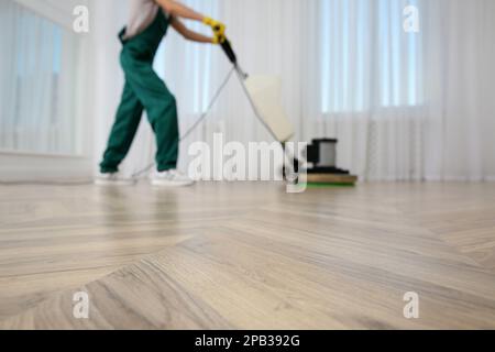 Vista offuscata del pavimento in parquet di pulizia professionale janitor con lucidatrice interna, primo piano Foto Stock