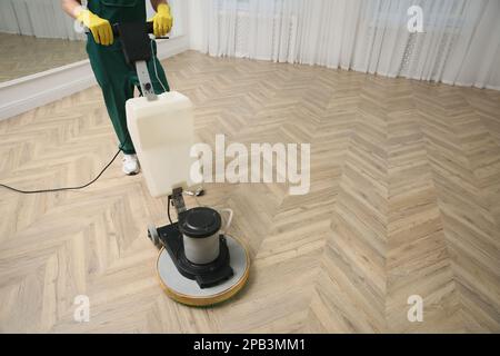 Janitor professionale per la pulizia di pavimenti in parquet con lucidatrice interna, primo piano. Spazio per il testo Foto Stock