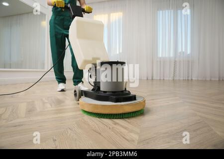 Janitor professionale per la pulizia di pavimenti in parquet con lucidatrice interna, primo piano. Spazio per il testo Foto Stock