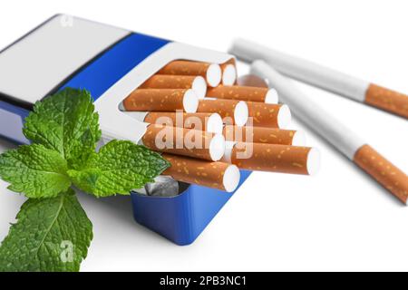 Pacchetto di sigarette mentolo e foglie di menta fresca su sfondo bianco, primo piano Foto Stock