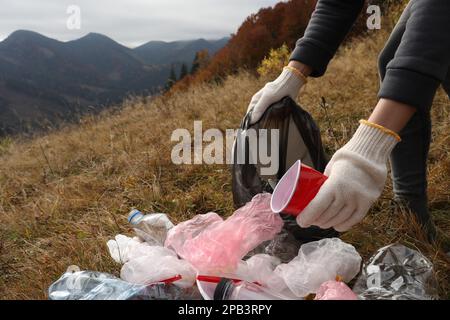 Donna con sacco di rifiuti raccolta rifiuti in natura, primo piano Foto Stock