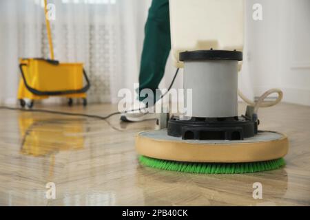 Janitor professionale per la pulizia di pavimenti in parquet con lucidatrice interna, primo piano. Spazio per il testo Foto Stock