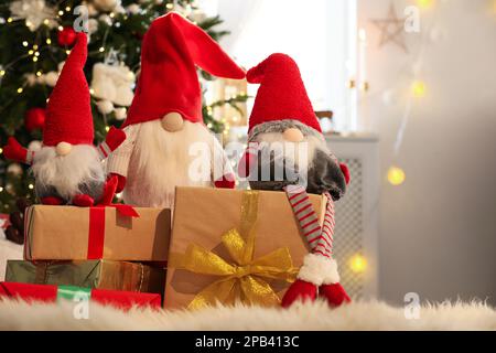 Simpatici gnomi di Natale e scatole regalo sul tappeto in camera Foto Stock