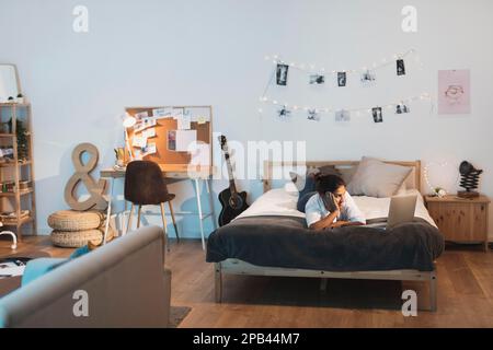 Donna che soggiorna nel letto e guarda un computer portatile Foto Stock