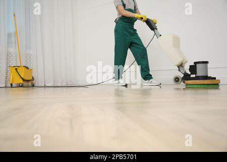 Janitor professionale per la pulizia di pavimenti in parquet con lucidatrice interna, primo piano. Spazio per il testo Foto Stock