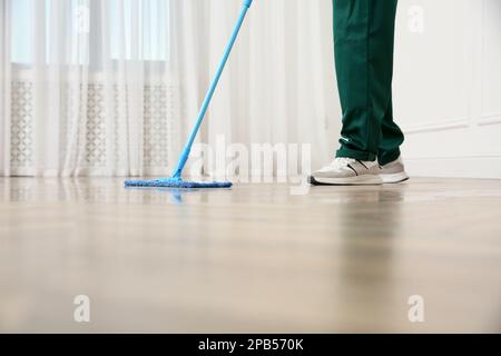 Janitor professionale per la pulizia del pavimento in parquet con spazzolone per interni, primo piano Foto Stock