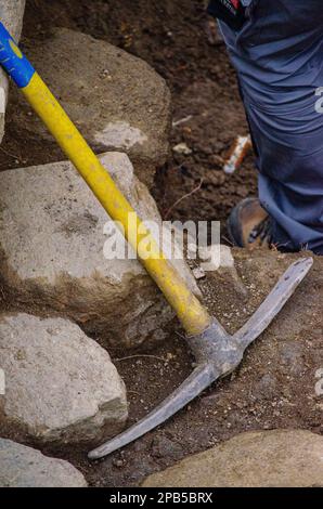 Un picchettino con manico in plastica appoggiato a un muro durante i lavori di scavo archeologico. Foto Stock