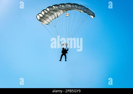 Paracadutista che scende con un paracadute bianco Foto Stock