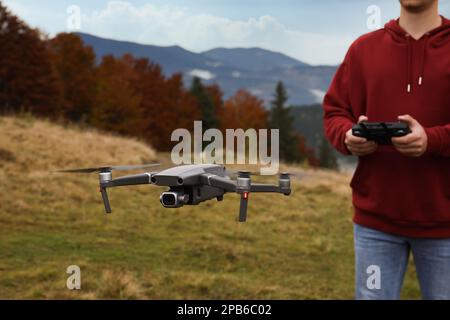 Uomo che lavora drone moderno con telecomando in montagna Foto Stock