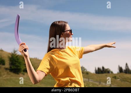 Giovane donna che lancia boomerang all'aperto nelle giornate di sole Foto Stock