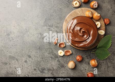 Saporito cioccolato nocciola spalmata e noci su tavola grigia, piatto. Spazio per il testo Foto Stock