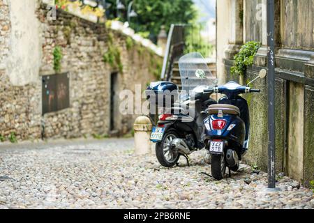 BERGAMO, ITALIA - APRILE 2022: Motociclette parcheggiate dalla stretta strada medievale della città bergamasca a nord-est di Milano. Vista panoramica su Città alta, la parte superiore della città Foto Stock