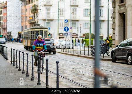 MILANO, ITALIA - APRILE 2022: Uomo in bicicletta su una strada trafficata nel centro di Milano, metropoli nella regione della Lombardia settentrionale d'Italia. Milano, Lombar Foto Stock