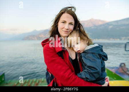 Giovane madre e suo figlio bambino su un traghetto. Mamma e bambino viaggiano in traghetto sul lago di Como in Italia. Andare in vacanza con i bambini piccoli. Foto Stock