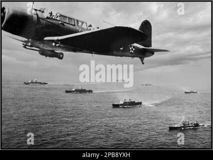 WW2 Atlantic Convoy Protection Convoy WS-12: A Vought SB2U Vindicator scout bombardiere da USS Ranger (CV-4) vola la pattuglia anti-sottomarina sul convoglio, mentre era in rotta per Città del Capo, Sudafrica, 27 novembre 1941. Il convoglio sembra fare un giro di formazione da colonna a linea in seguito. I trasporti a due stack nella prima riga sono USS West Point (AP-23) -- left --; USS Mount Vernon (AP-22) e USS Wakefield (AP-21). Incrociatori pesanti, sul lato destro della prima fila e a metà della seconda, sono la USS Vincennes (CA-44) e la USS Quincy (CA-39). Foto Stock