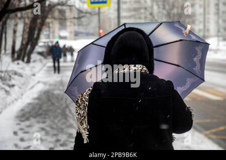 Mosca, Russia. 12th marzo, 2023. Una donna si rifugia sotto un ombrello durante una nevicata a Mosca, Russia. La marcia è prevista a Mosca per condizioni di nevischio, pioggia e ghiaccio. Foto Stock