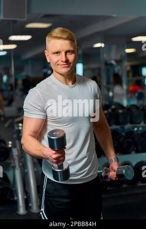 il ragazzo biondo si sta allenando in palestra Foto Stock