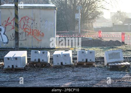 Blocchi di cemento su pallet preparati per la costruzione di un attraversamento ferroviario posto a terra con costruzione di infrastrutture ferroviarie in background Foto Stock