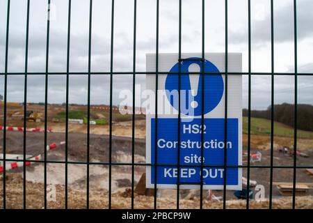 Wendover Dean, Buckinghamshire, Regno Unito. 12th marzo, 2023. Un cartello del cantiere del HS2. Questa settimana è stato annunciato che la fase da Birmingham a Crewe del HS2 è stata messa in attesa a causa dell'aumento dei costi. I costi attuali del progetto sono enormemente superiori al budget e si prevede che superino i 100 miliardi di sterline. HS2 sta avendo un impatto estremamente negativo sui residenti che vivono lungo la linea alcuni dei quali hanno fatto demolire le loro case e gli agricoltori hanno fatto i loro terreni presi entro il HS2, ma presumibilmente non hanno ancora ricevuto alcuna compensazione. Credit: Maureen McLean/Alamy Live News Foto Stock