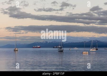 Le barche che galleggiano nel porto di Ushuaia Argentina al tramonto nel canale di Beagle del Sud America sono crogiolate alla luce del sole all'ora d'oro del tramonto Foto Stock