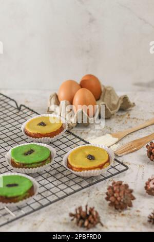 KUE Kuala Lumpur o torta di fango, una tradizionale torta indonesiana fatta di patate, farina, uova e latte di cocco con una spruzzata di uva passa servita su una griglia per torte. Foto Stock