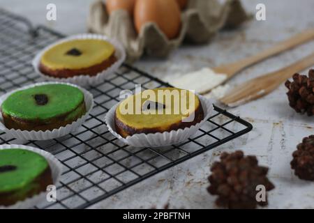 KUE Kuala Lumpur o torta di fango, una tradizionale torta indonesiana fatta di patate, farina, uova e latte di cocco con una spruzzata di uva passa servita su una griglia per torte. Foto Stock