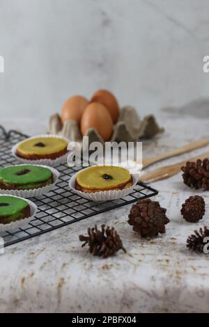 KUE Kuala Lumpur o torta di fango, una tradizionale torta indonesiana fatta di patate, farina, uova e latte di cocco con una spruzzata di uva passa servita su una griglia per torte. Foto Stock
