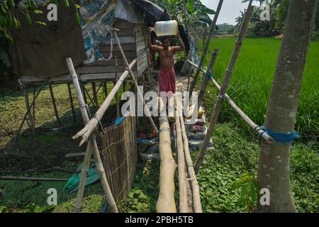 12 marzo 2023, Kolkata, bengala Occidentale, India: Una persona sta trasportando un vaso d'acqua che attraversa una piscina di legno alla periferia di Kolkata. (Credit Image: © Sudipta Das/Pacific Press via ZUMA Press Wire) SOLO PER USO EDITORIALE! Non per USO commerciale! Foto Stock