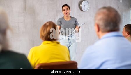 Giovane insegnante di sesso femminile che spiega il soggetto a studenti maturi Foto Stock