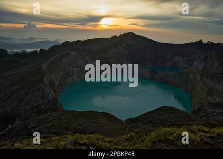 Suggestiva alba con cielo nuvoloso sul vulcano Monte Kelimutu, in primo piano il lago cratere blu turchese. Foto Stock