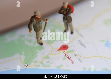 figura in miniatura di un esploratore in posa su una mappa digitale tramite un telefono cellulare Foto Stock