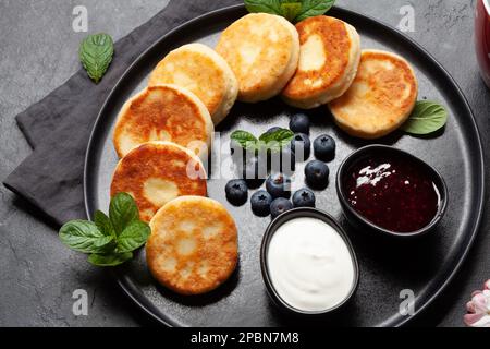 Frittelle caserette con marmellata di frutti di bosco, panna acida e frutti di bosco Foto Stock