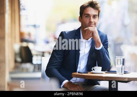 Unisciti a me per un caffè. Ritratto di un giovane uomo d'affari seduto in un bar all'aperto. Foto Stock