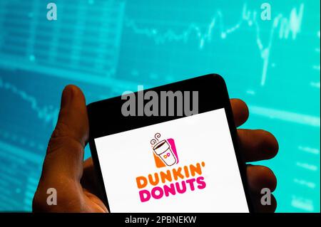 Cina. 15th Feb, 2023. In questa illustrazione della foto, il logo Dunkin' Donuts della catena multinazionale americana di caffè e snack viene visualizzato su uno smartphone con un grafico dell'indice della borsa economica sullo sfondo. (Credit Image: © Budrul Chukrut/SOPA Images via ZUMA Press Wire) SOLO PER USO EDITORIALE! Non per USO commerciale! Foto Stock