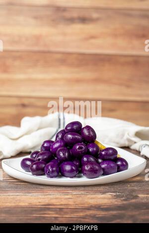 Oliva Kalamata con sapore di mirtilli. Olive viola su sfondo di legno. Foto Stock