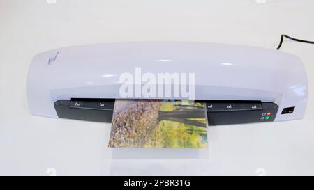 Una macchina per la laminazione di foto e documenti con plastica. Laminatrice bianca da tavolo, primo piano Foto Stock