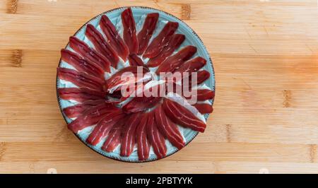 un piatto di fette di prosciutto iberic su un piatto posto sopra un tavolo di legno. Jamon tradizionale spagnolo Foto Stock