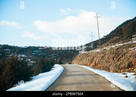 Strada in montagna circondata da una coperta di neve Foto Stock