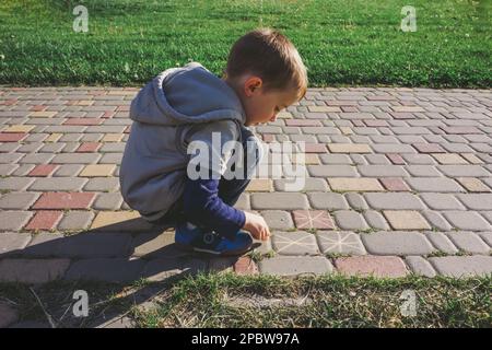 Ragazzo che usava il gesso sul marciapiede su un passaggio pedonale Foto Stock