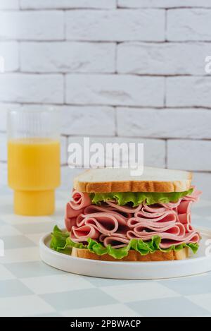 sandwich con prosciutto, formaggio ed erbe aromatiche su un piatto. succo d'arancia Foto Stock