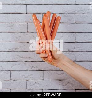 mano che tiene hot dog salsicce Foto Stock